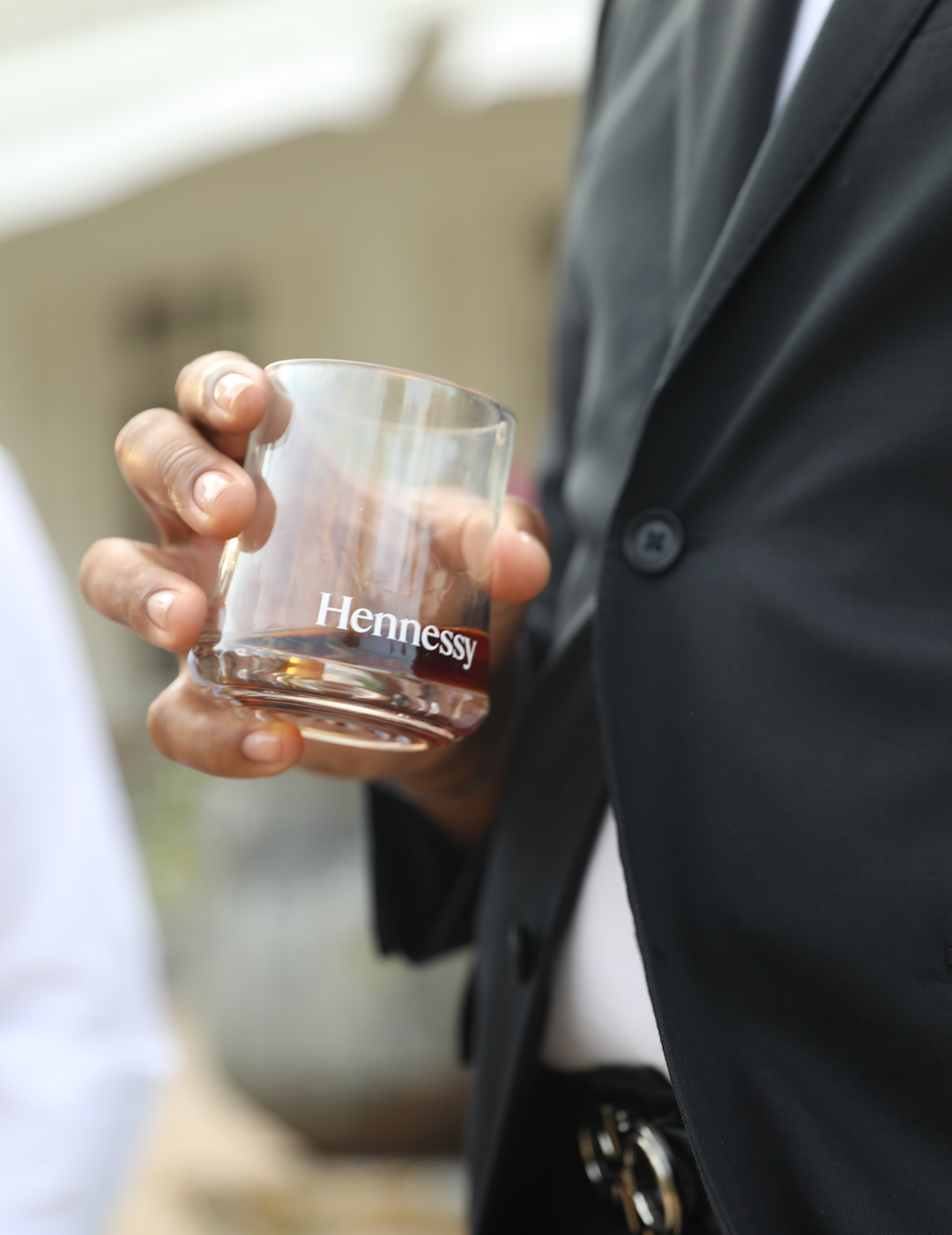 A person holding a glass of Hennessy